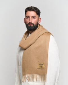 A folded green tartan cashmere scarf with soft lighting highlighting the weave.